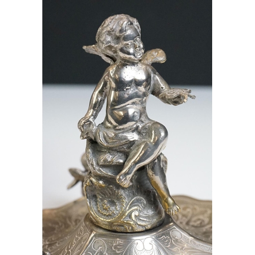 129 - A Victorian silver plated table centrepiece with a winged cherub holding a butterfly above three sha... 