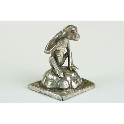 278 - Continental white metal figurine modelled as a squatting monkey, red glass eyes, height approx 3.5cm... 