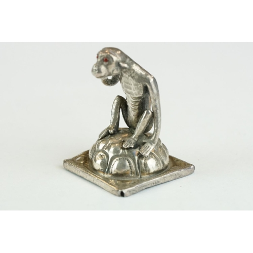 278 - Continental white metal figurine modelled as a squatting monkey, red glass eyes, height approx 3.5cm... 