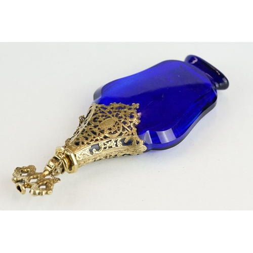 289 - 18th century blue glass gilt scent bottle, faceted hourglass body raised on foot, pierced gilt colla... 