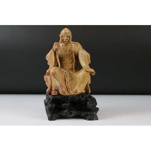 164 - Chinese Soapstone Carving of a Seated Elder, raised on a carved stone base in the form of a rocky ou... 