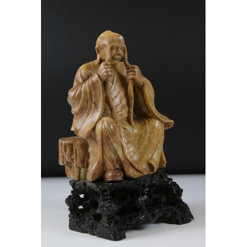 164 - Chinese Soapstone Carving of a Seated Elder, raised on a carved stone base in the form of a rocky ou... 