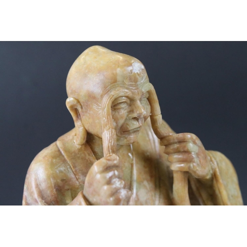 164 - Chinese Soapstone Carving of a Seated Elder, raised on a carved stone base in the form of a rocky ou... 