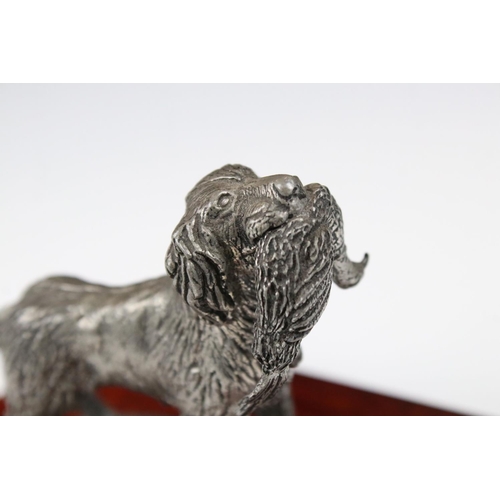 204 - Metal figurine of a gun dog carrying a pheasant, on a wooden base