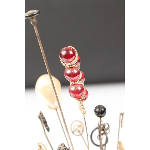 214 - A collection of hat and cravat pins held within two hat pin holders.