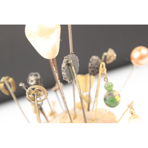 214 - A collection of hat and cravat pins held within two hat pin holders.