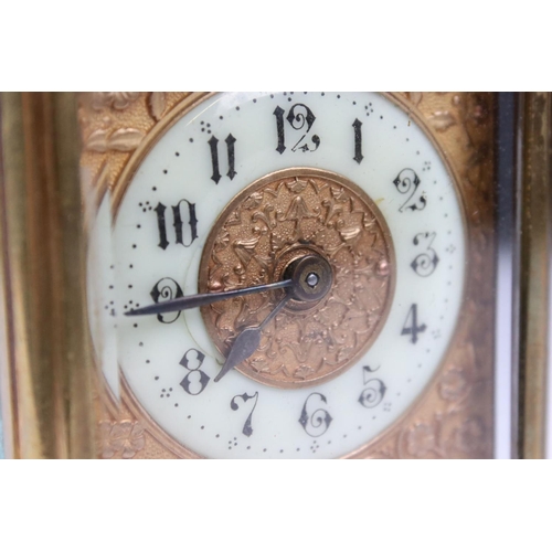 223 - An antique brass cased carriage clock with bevelled glass panels and decorative face and dial, compl... 