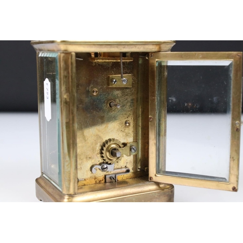 223 - An antique brass cased carriage clock with bevelled glass panels and decorative face and dial, compl... 