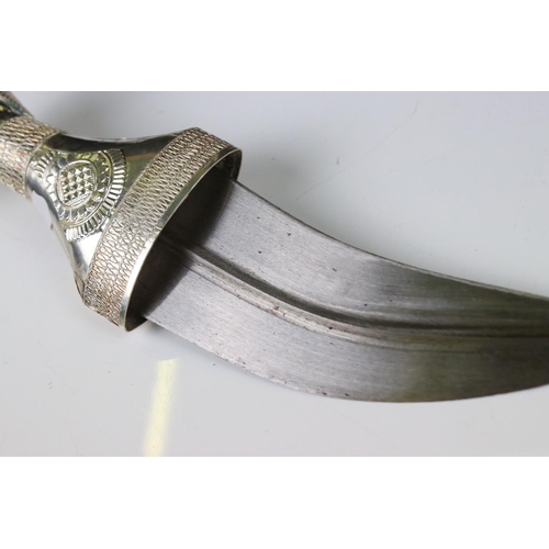 241 - An Asian Jambiya knife / dagger in ornamental white metal sheath.