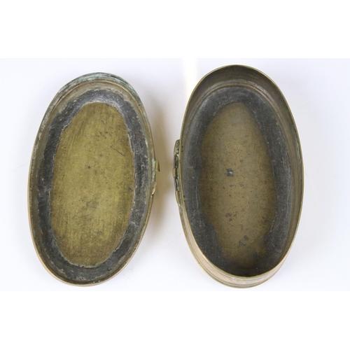 292 - An antique 18th century oval brass snuff box with ornate chased decoration.