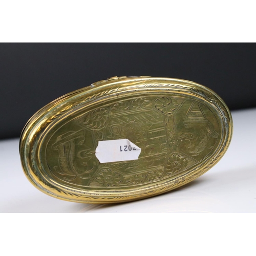 292 - An antique 18th century oval brass snuff box with ornate chased decoration.