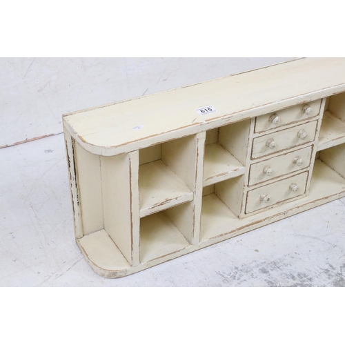 615 - Painted pine wall shelf of eight pigeonholes & four drawers, 89cm long x 32cm