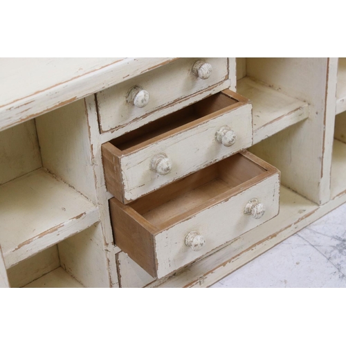 615 - Painted pine wall shelf of eight pigeonholes & four drawers, 89cm long x 32cm