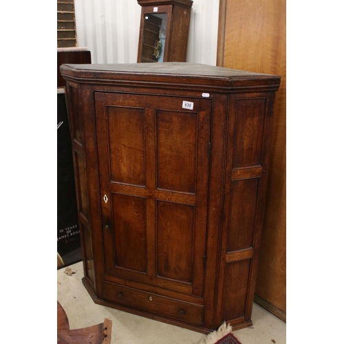 630 - George III Oak Hanging Corner Cupboard, the single panel door opening to three shelves, drawer below... 