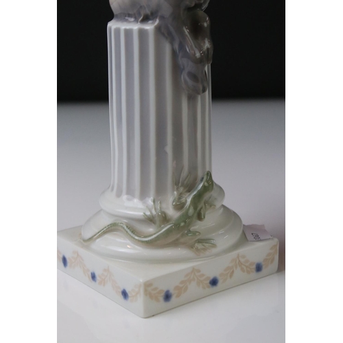 3 - Two Royal Copenhagen porcelain figures to include a faun playing a mouth organ seated on fluted colu... 
