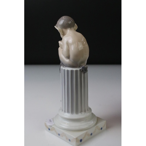 3 - Two Royal Copenhagen porcelain figures to include a faun playing a mouth organ seated on fluted colu... 