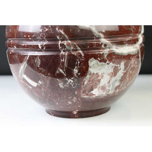 128 - Polished marble vase of spherical footed form, with tones of red and off-white, moulded rim and doub... 