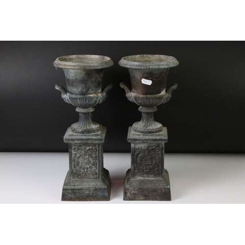 145 - Pair of bronze twin-handled urns mounted on square spelter columns with relief cast scrolling and fo... 