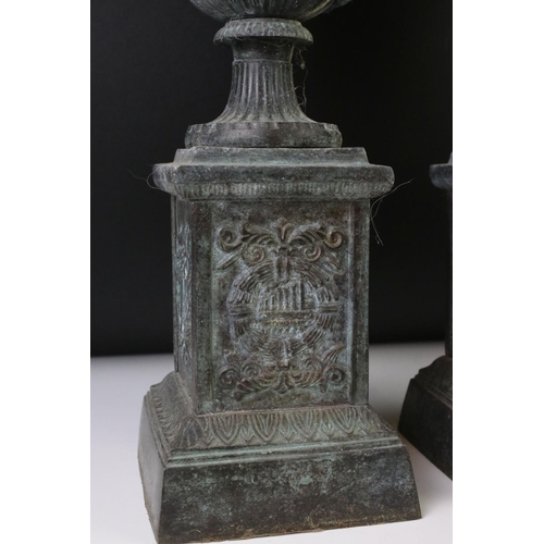 145 - Pair of bronze twin-handled urns mounted on square spelter columns with relief cast scrolling and fo... 
