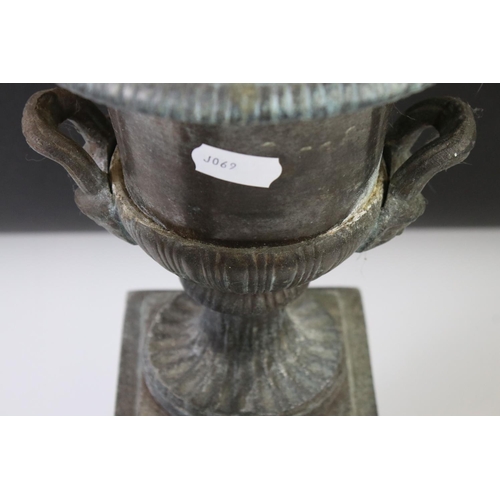 145 - Pair of bronze twin-handled urns mounted on square spelter columns with relief cast scrolling and fo... 