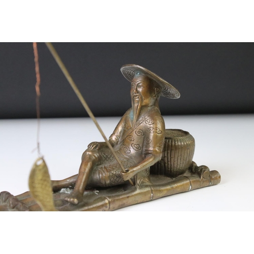 150 - Chinese bronze figure of a fisherman on a bamboo raft, with rod in hand, measures approx 28cm long