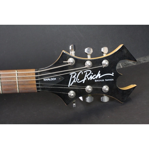 843 - Guitar - B.C. Rich Warlock Bronze Series electric guitar in black.  Various band stickers have been ... 