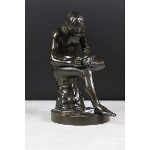 150 - Bronze figure of a nude male seated on a tree stump, checking the sole of his foot, raised on a circ... 