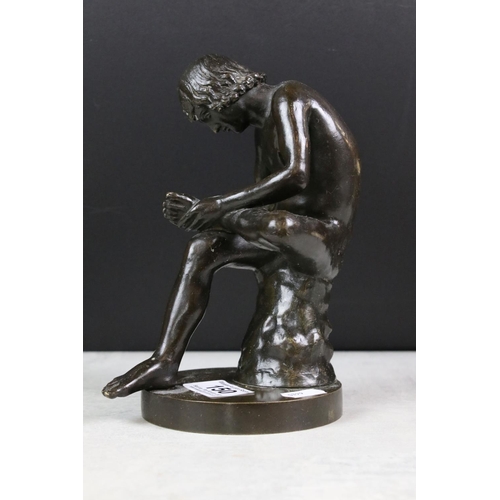 150 - Bronze figure of a nude male seated on a tree stump, checking the sole of his foot, raised on a circ... 