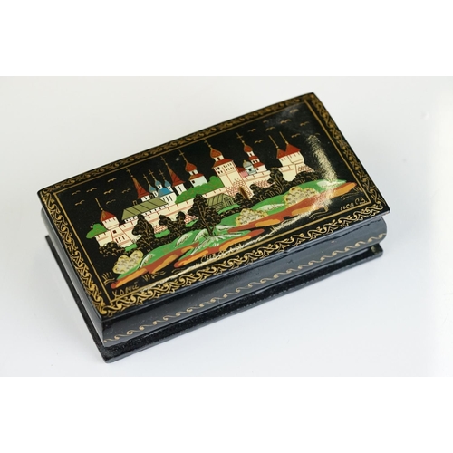 256 - Two Russian lacquerware trinket boxes, both signed to the lids, together with a similar dish.