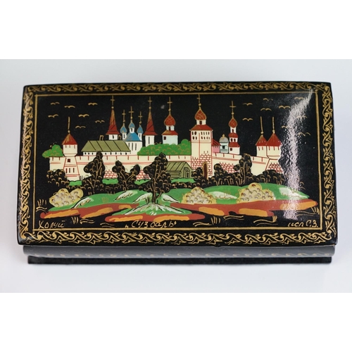 256 - Two Russian lacquerware trinket boxes, both signed to the lids, together with a similar dish.