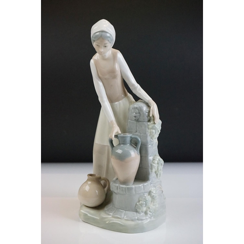 38 - Nao porcelain figure of a girl filling urn at the water well, 29cm high, together with a Lladro porc... 