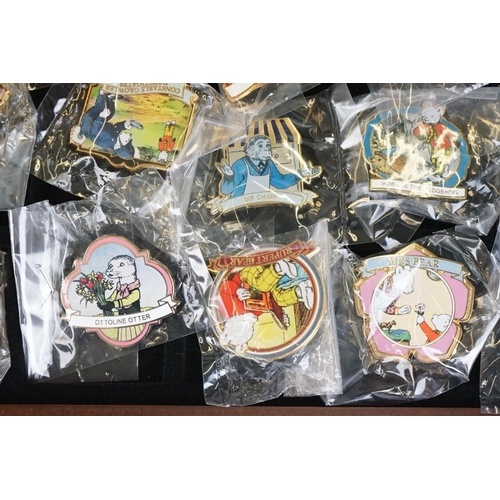 293 - A large collection of over fifty collectable Rupert The Bear pin badges contained within a glass top... 