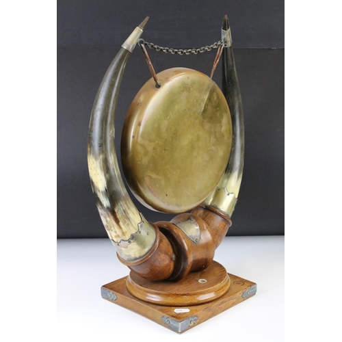 160 - Edwardian Oak and Horn dinner gong, the central brass gong supported by two bovine horns mounted upo... 