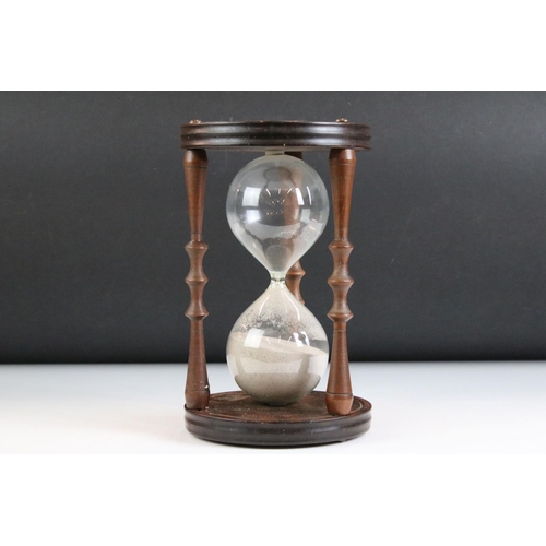 160 - Large Glass Sand Timer held on a Mahogany Circular Frame with turned supports, 24cm high