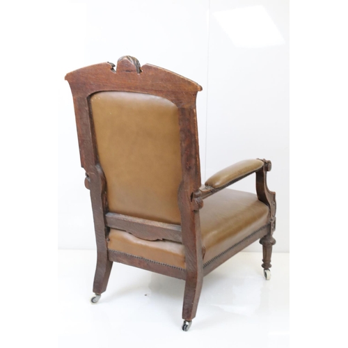 585 - Victorian Carved Oak Open Armchair, the top rail carved with a face mask, raised on castors, 66cm wi... 