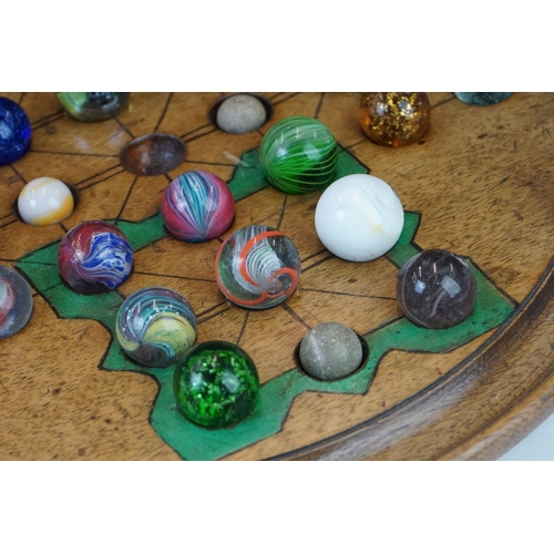 220 - A turned wooden solitaire board together with associated marbles.