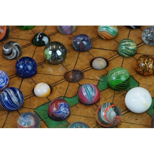 220 - A turned wooden solitaire board together with associated marbles.