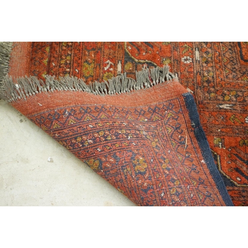 563 - Eastern Wool Red ground Rug with floral and geometric design within a border, 215cm x 280cm