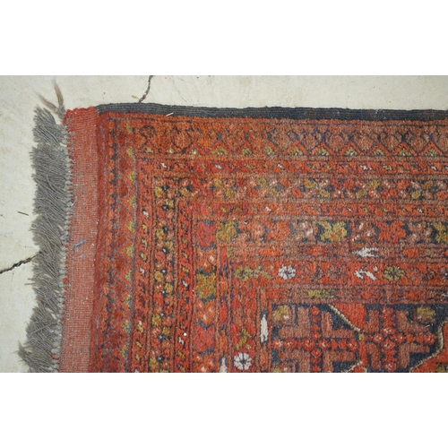 563 - Eastern Wool Red ground Rug with floral and geometric design within a border, 215cm x 280cm