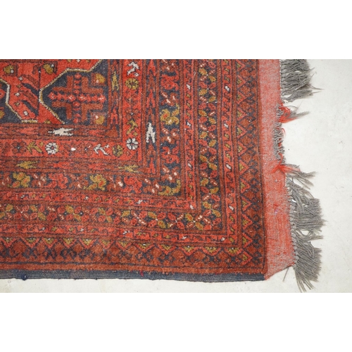 563 - Eastern Wool Red ground Rug with floral and geometric design within a border, 215cm x 280cm