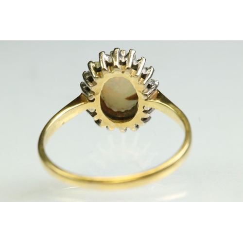35 - Opal and diamond 18ct yellow and white gold set cluster ring, the precious white opal displaying vio... 
