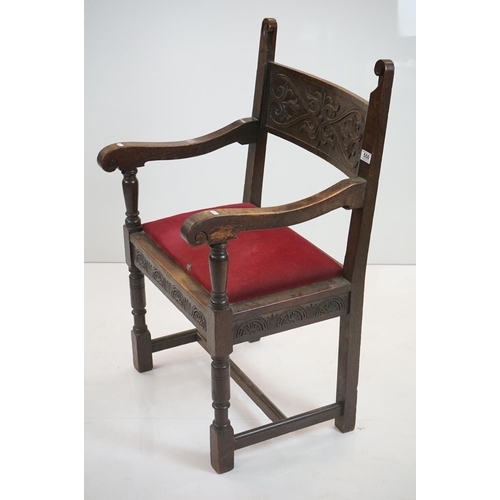 578 - In the manner of Liberty of London, Gothic Revival Oak Elbow Chair with carved back rail and upholst... 