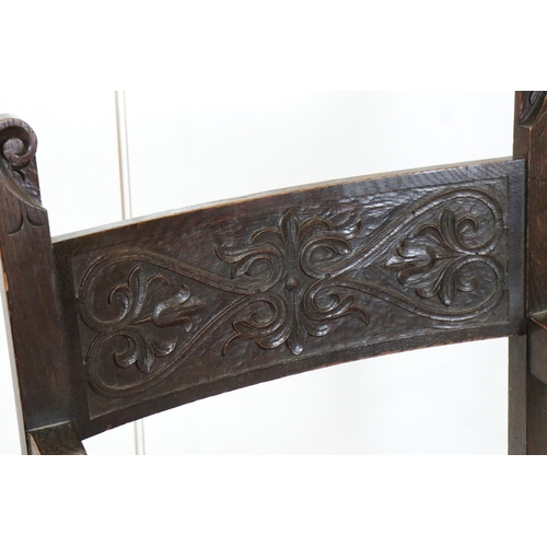 578 - In the manner of Liberty of London, Gothic Revival Oak Elbow Chair with carved back rail and upholst... 