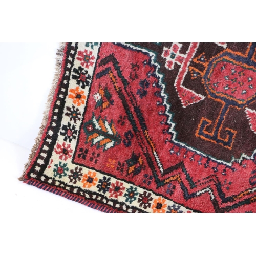 582 - Eastern Red Ground Rug with geometric pattern within a shallow border, approximately 145cm x 109cm