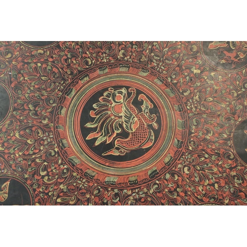 624 - Burmese Red and Black Lacquered Octagonal Folding Table decorated with images of figures, birds, ani... 