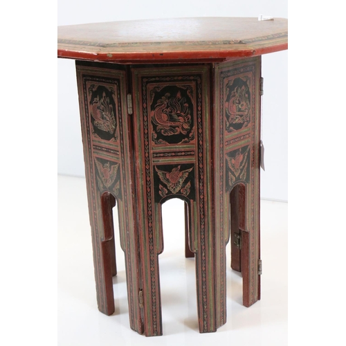 624 - Burmese Red and Black Lacquered Octagonal Folding Table decorated with images of figures, birds, ani... 