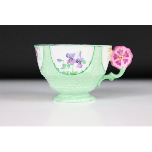 21 - Aynsley 1930's ' Flower Handle ' Trio, each piece hand painted with panels of flowers on a green gro... 