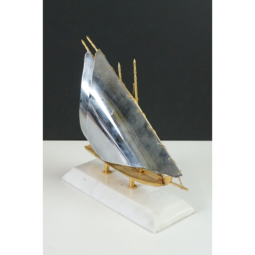 148 - Gold Plated Model of a Yacht bearing the United Arab Emirates Flag, raised on a marble base, 22cm hi... 