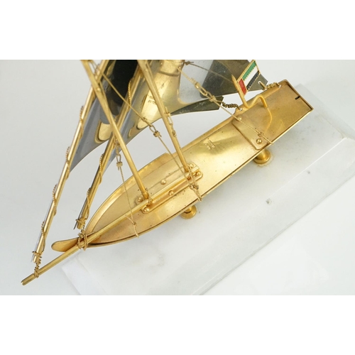 148 - Gold Plated Model of a Yacht bearing the United Arab Emirates Flag, raised on a marble base, 22cm hi... 