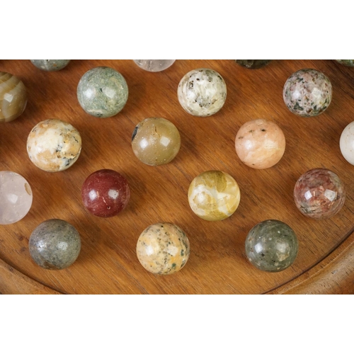 206 - A turned wooden solitaire board complete with polished semi precious stone marbles.